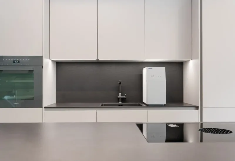 A pale minimal kitchen with a built-in wall oven and a run of handleless cabinets.