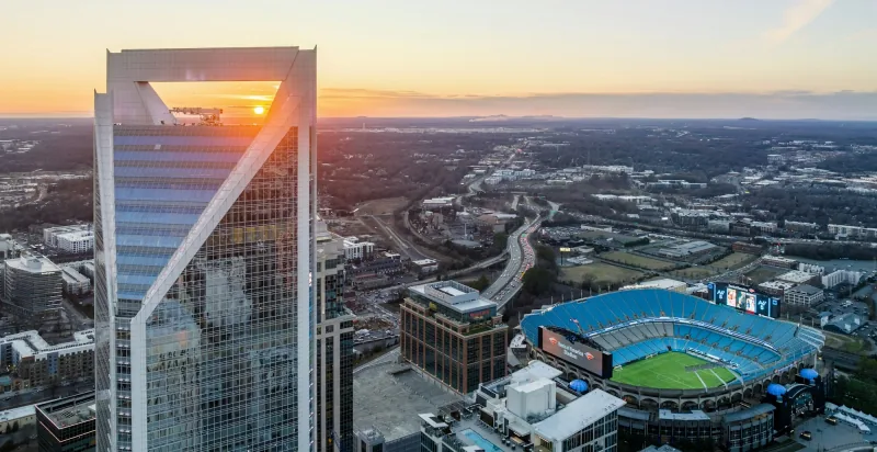Uptown Charlotte photographed from the air at sunset, with the stadium below the towers of the city centre.